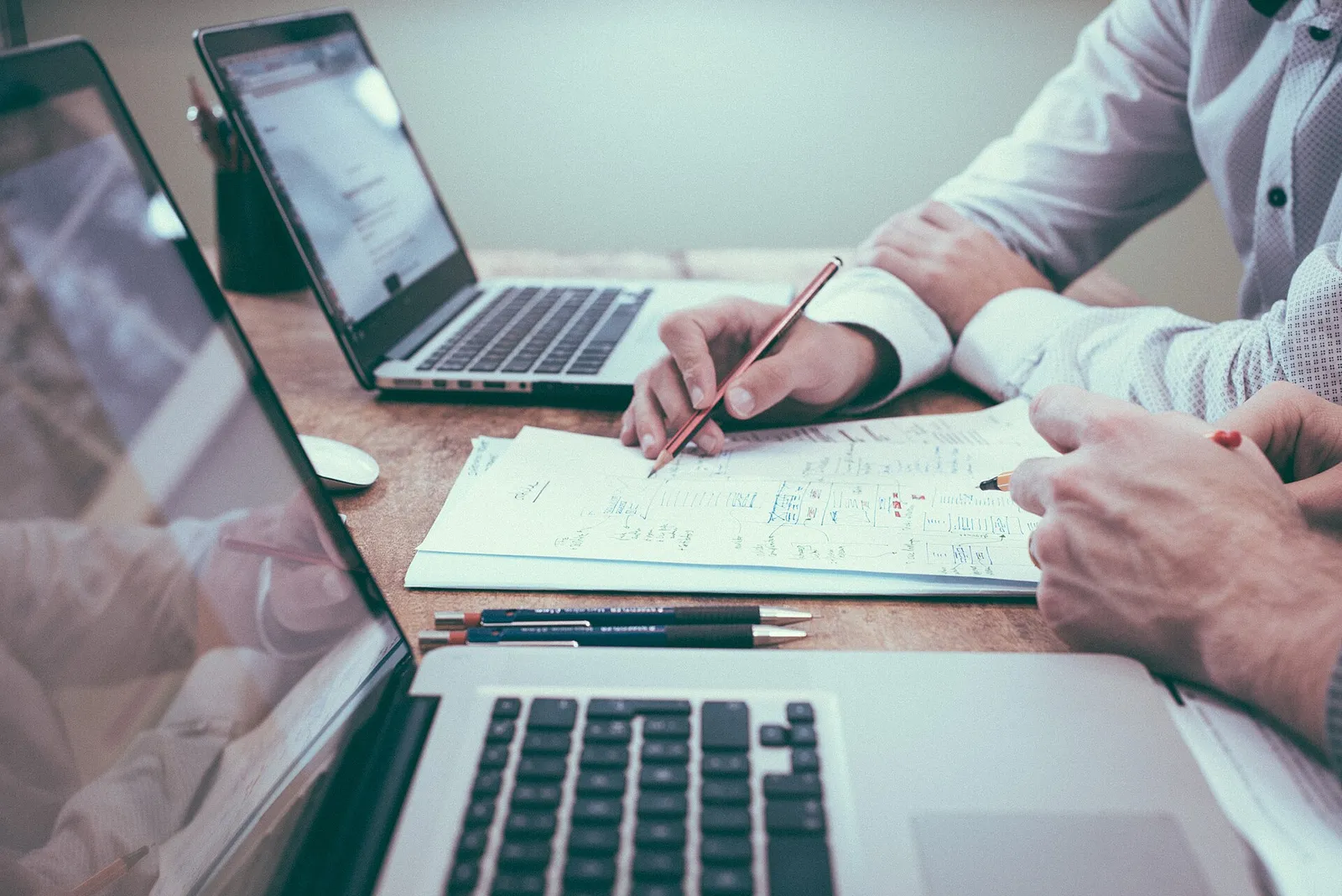 Un equipo de trabajo en una mesa con ordenadores portátiles