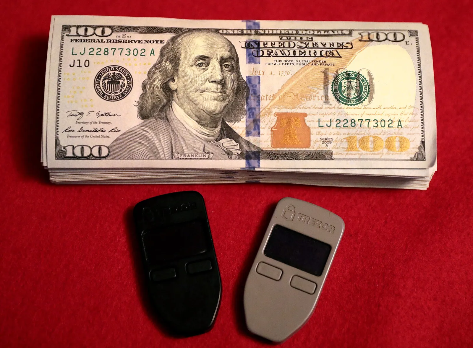 Dos monederos físicos (hardware wallets) para criptomonedas junto a billetes (imagen de archivo)