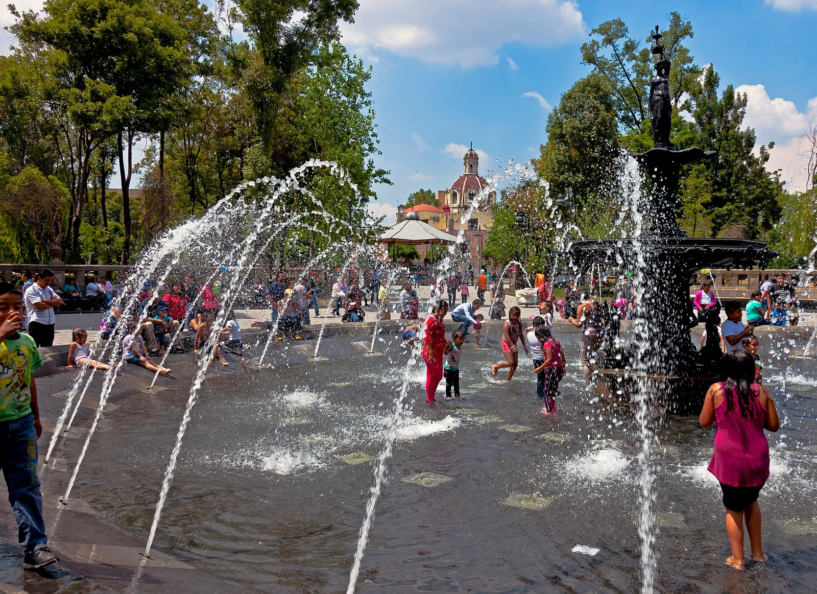 Niños se refrescan jugando en una fuente en verano (imagen de archivo)