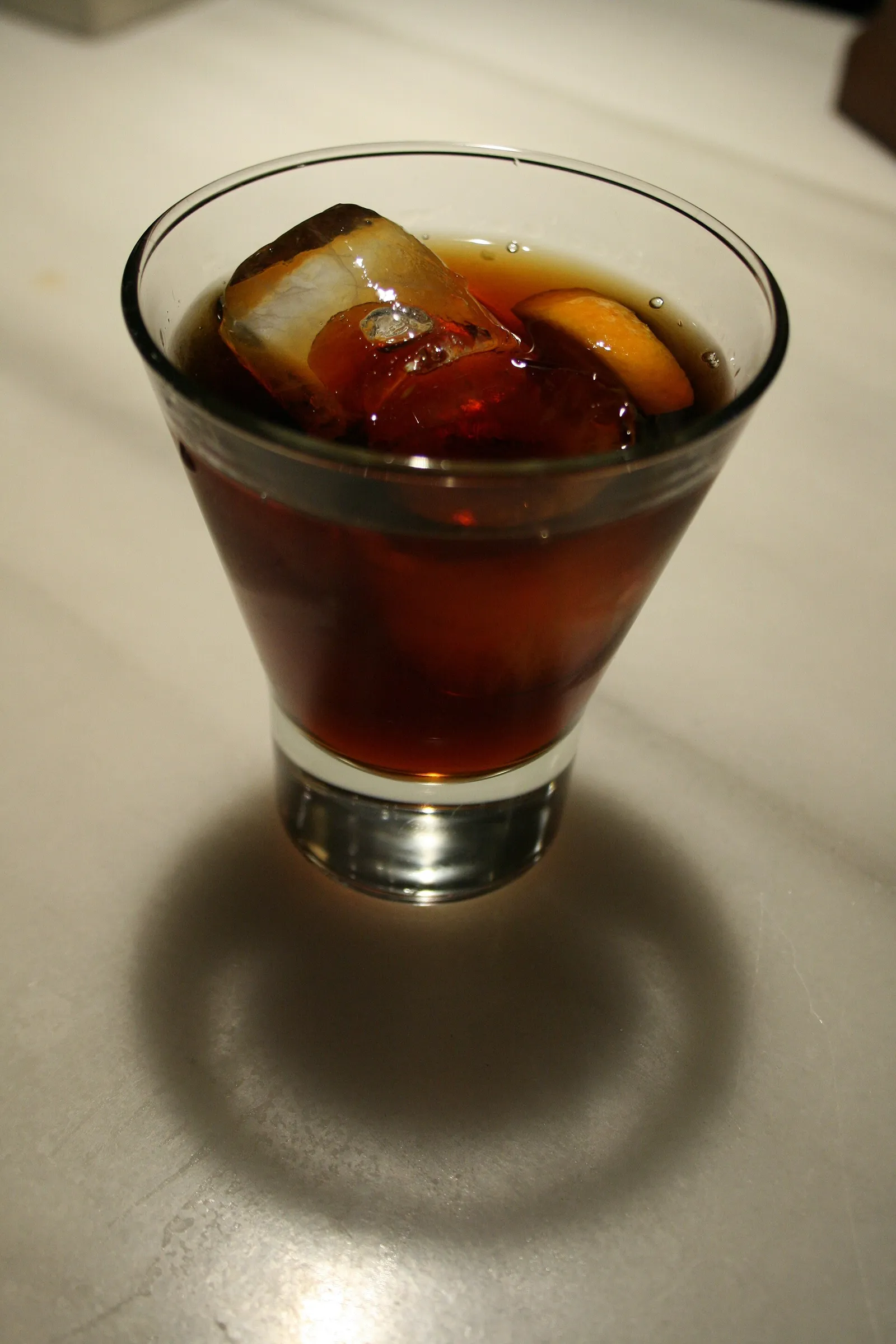Una copa de vermut servida con hielo y una rodaja de naranja