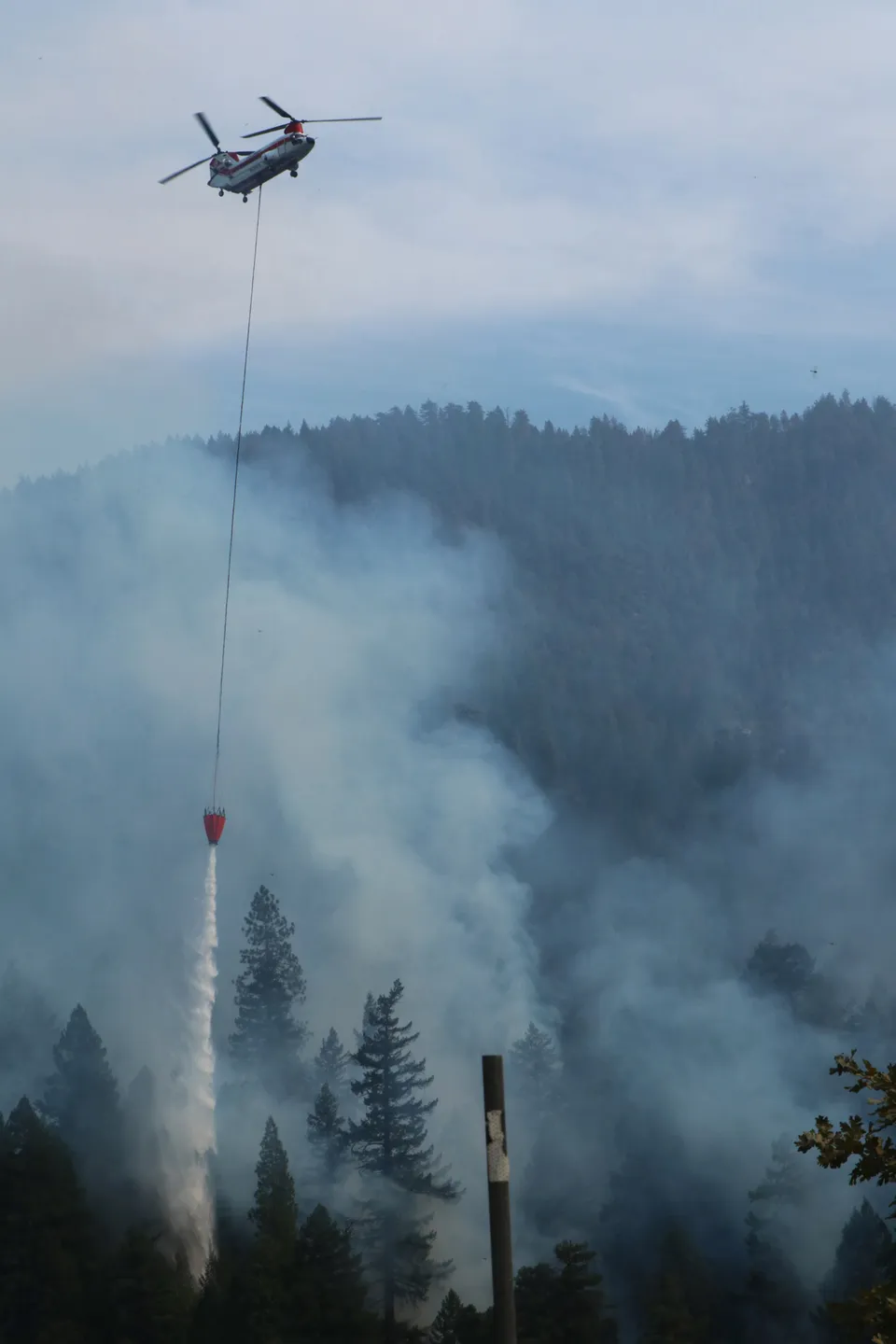 Un helicóptero descarga agua sobre un incendio forestal