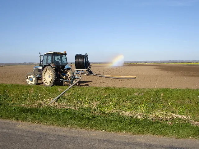 Aspersor de riego lanzando agua sobre un campo