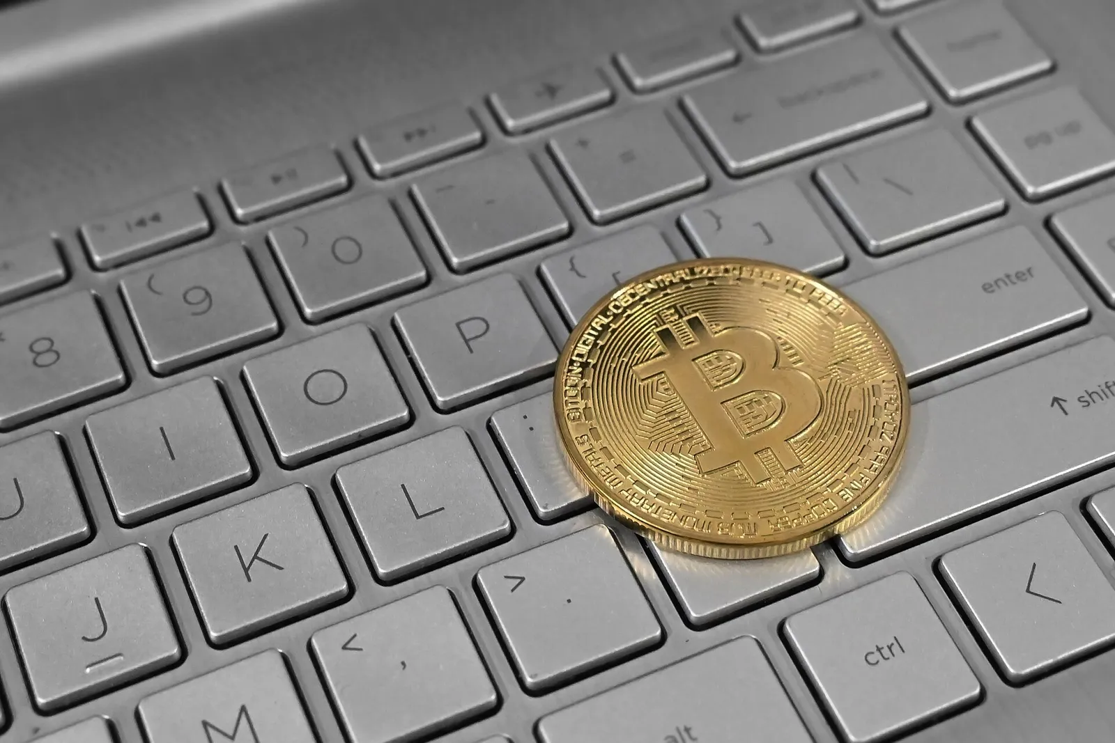 Una moneda física de bitcoin sobre el teclado de un ordenador portátil
